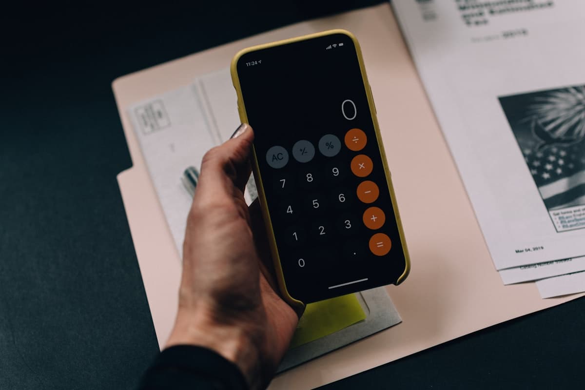 Hand holding a phone calculator over invoice documents