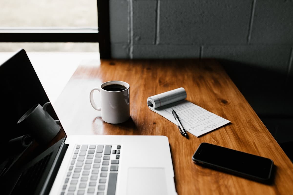 Laptop, notebook and coffee on a wooden desk — content writing setup