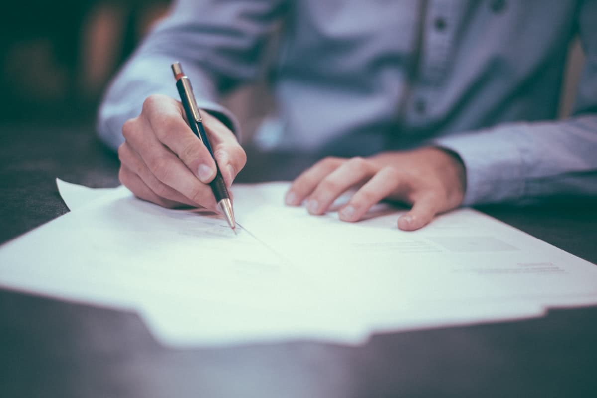 Hands signing a contract document with a pen